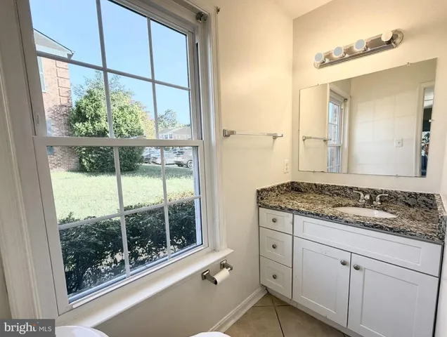 a bathroom with a granite countertop sink and next to a window