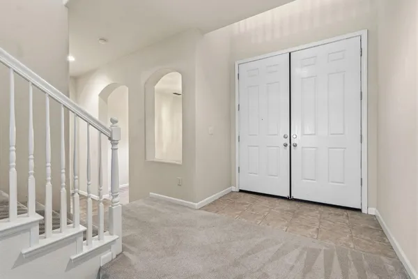 a view of an empty room with wooden floor and kitchen