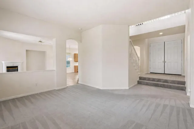 a view of an empty room with wooden floor and kitchen
