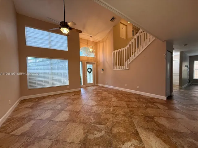 a view of an empty room with window and chandelier fan