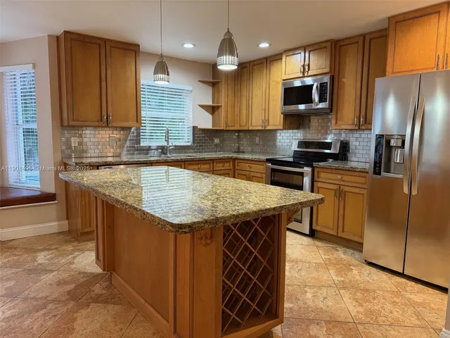 a kitchen with stainless steel appliances granite countertop a sink stove microwave and refrigerator