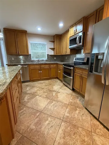 a large kitchen with granite countertop a stove a sink a microwave and refrigerator