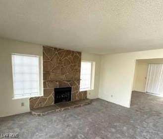 2813 Cacto Court Henderson, NV 89074 - Photo 28 of 28 Unfurnished living room featuring a stone fireplace, carpet flooring, and a textured ceiling