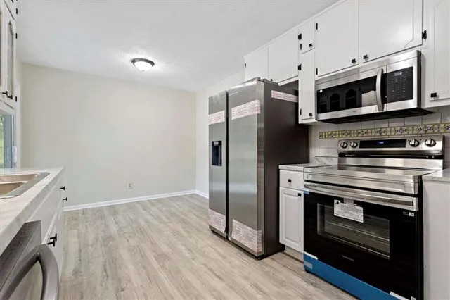 a kitchen with stainless steel appliances a stove a microwave and a hard wood floors