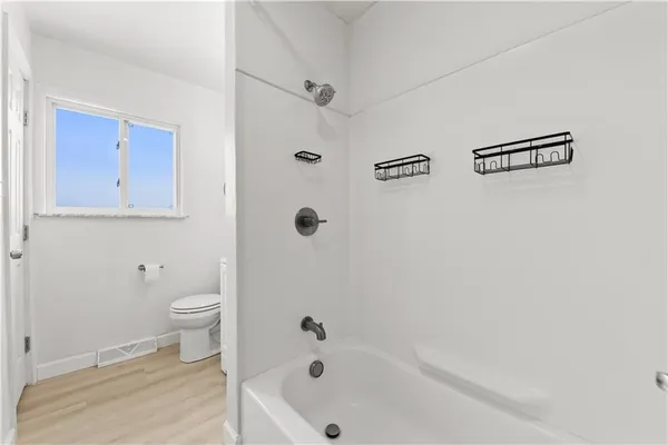 a bathroom with a bathtub shower and toilet