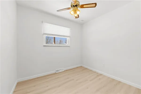 an empty room with a window and a fan