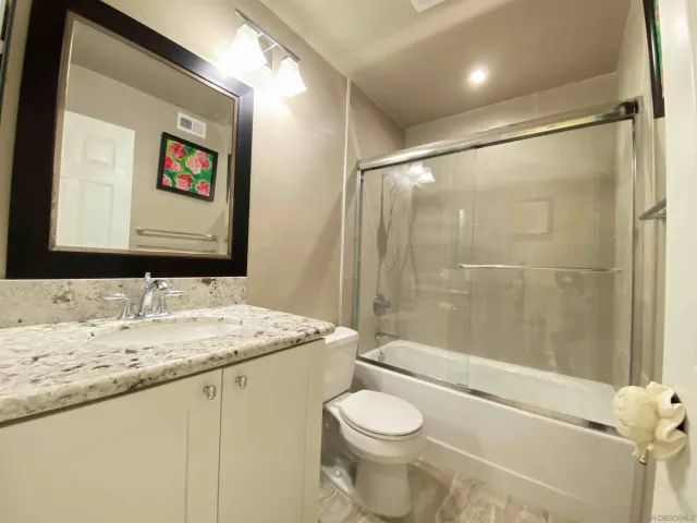 a bathroom with a granite countertop sink toilet and shower