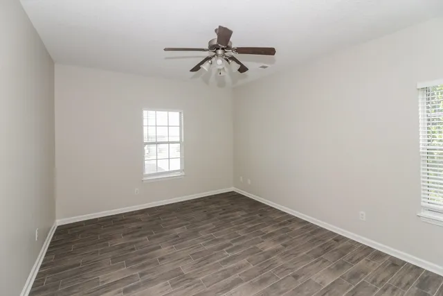 a view of empty room with wooden floor and fan