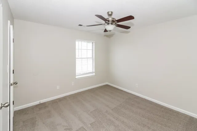 an empty room with a window and a fan