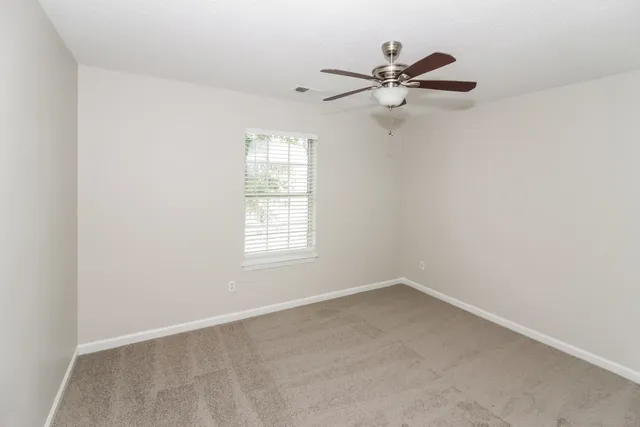 an empty room with window and a ceiling fan