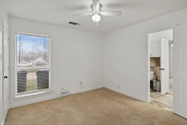 an empty room with windows and fan