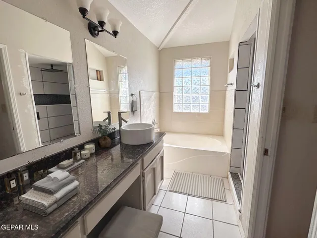 a spacious bathroom with a granite countertop sink mirror and bathtub