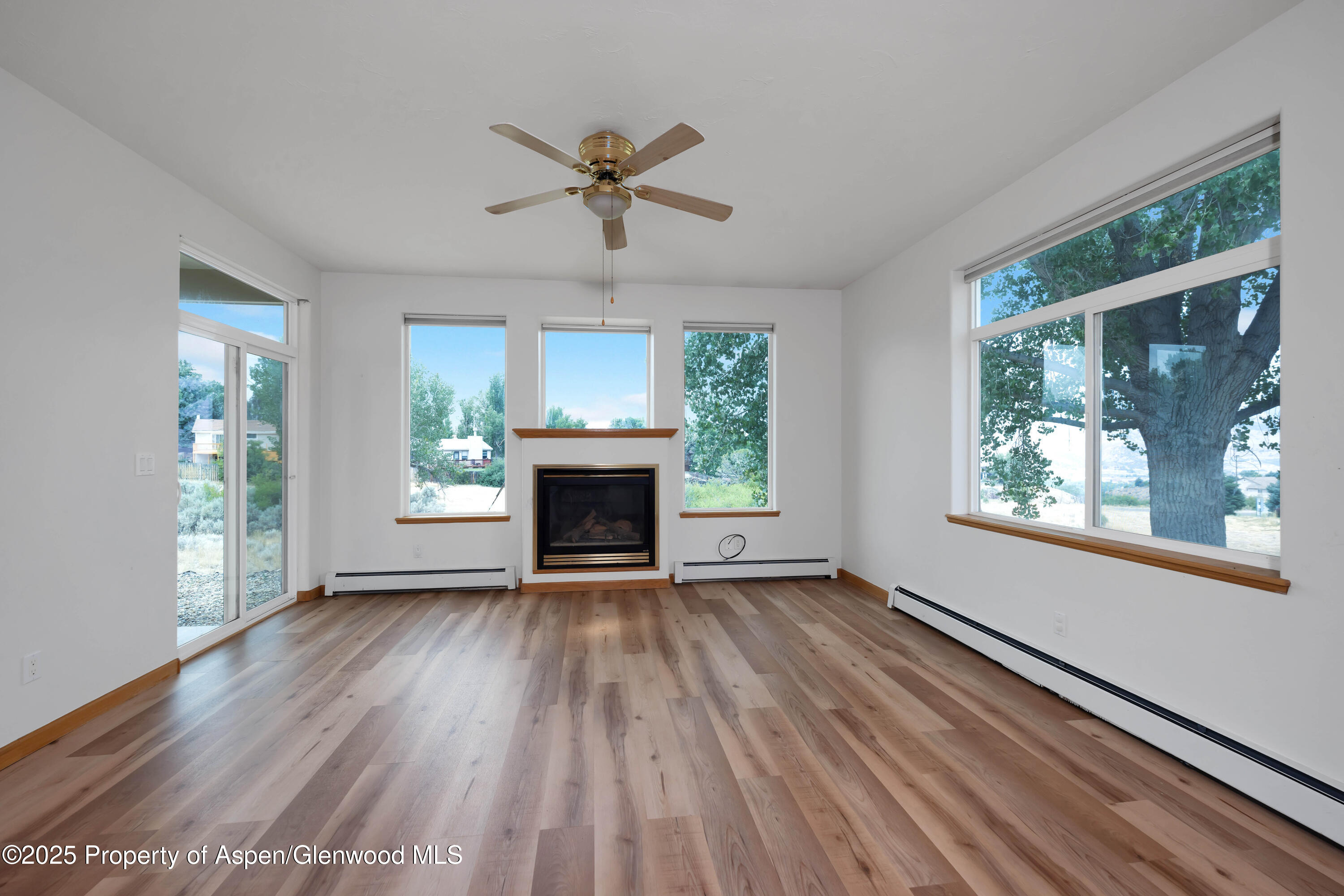 250 Limberpine Circle Battlement Mesa, CO 81635 - Photo 7 of 34 an empty room with windows a fireplace and wooden floor
