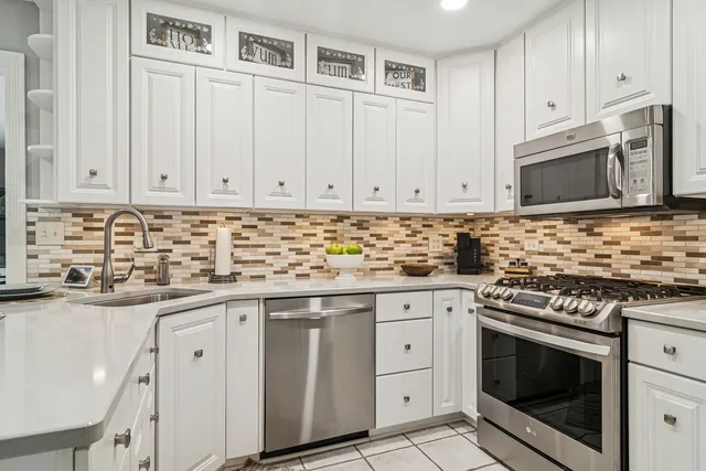 a kitchen with granite countertop white cabinets and stainless steel appliances