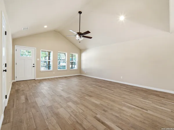a view of an empty room with a window and wooden floor
