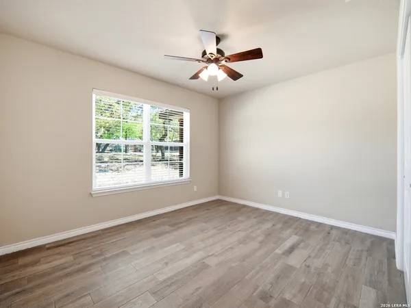 an empty room with wooden floor fan and windows