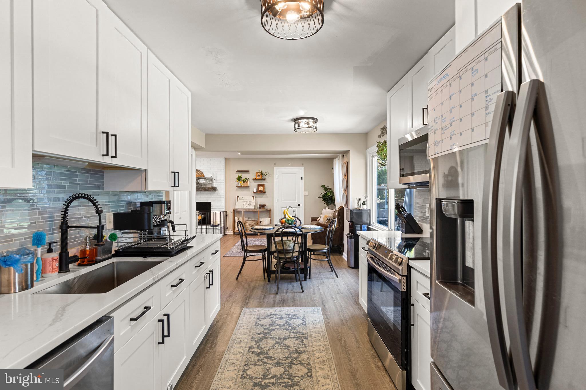 6666 Kelly Road Warrenton, VA 20187 - Photo 7 of 34 a kitchen with stainless steel appliances granite countertop a refrigerator a sink dishwasher a stove and white countertops with wooden floor