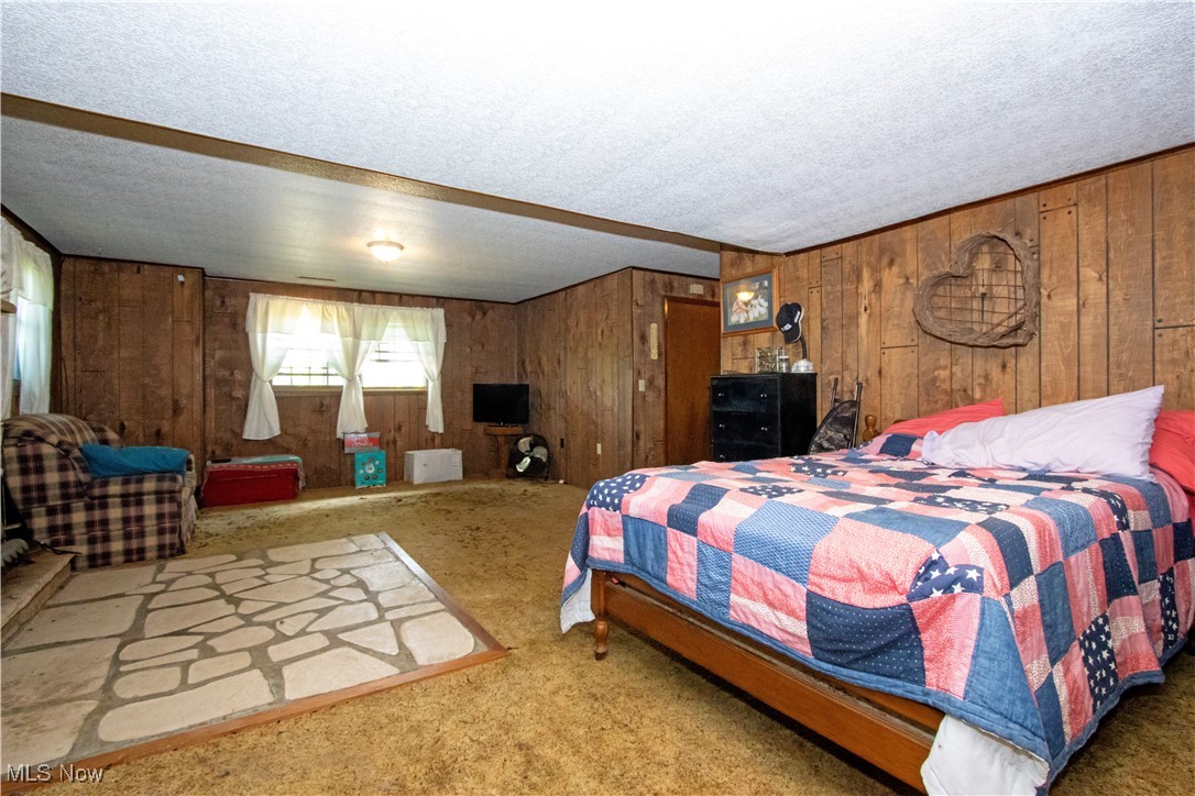 1292 Cinder Road Southeast Carrollton, OH 44615 - Photo 41 of 42 Carpeted bedroom featuring wooden walls and a textured ceiling