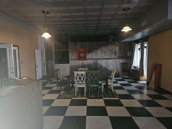 a room with a black white checkered floor with a gaming machine and dining table