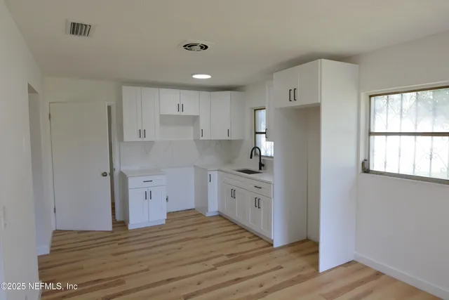 a kitchen with granite countertop white cabinets and wooden floor