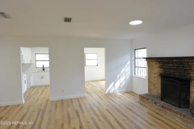 a view of empty room with wooden floor and fireplace