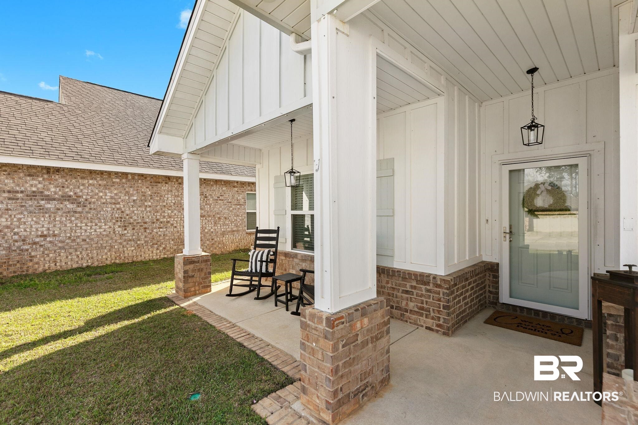 31650 Memphis Loop Daphne, AL 36527 - Photo 4 of 68 View of exterior entry featuring board and batten siding, a porch, brick siding, and a yard