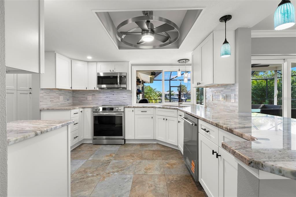 4003 Headsail Drive New Port Richey, FL 34652 - Photo 13 of 50 a kitchen with granite countertop a stove top oven a sink a counter top space and cabinets