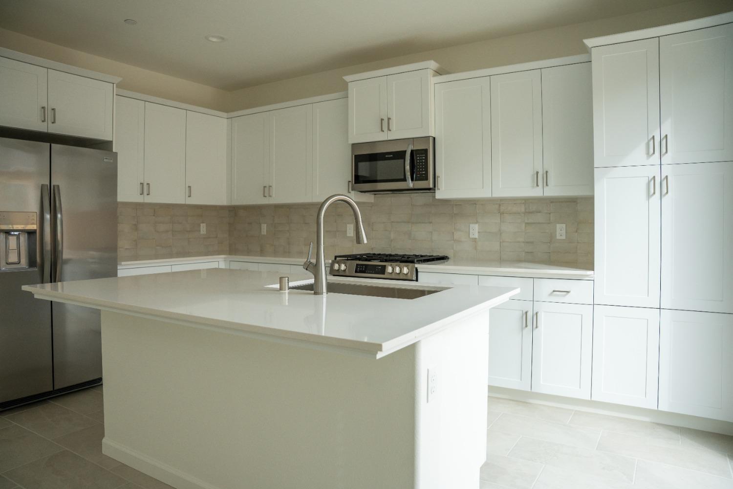 694 Thomas Way Madera, CA 93636 - Photo 5 of 27 a kitchen with stainless steel appliances a sink a stove a microwave a refrigerator a white cabinets and a counter top space