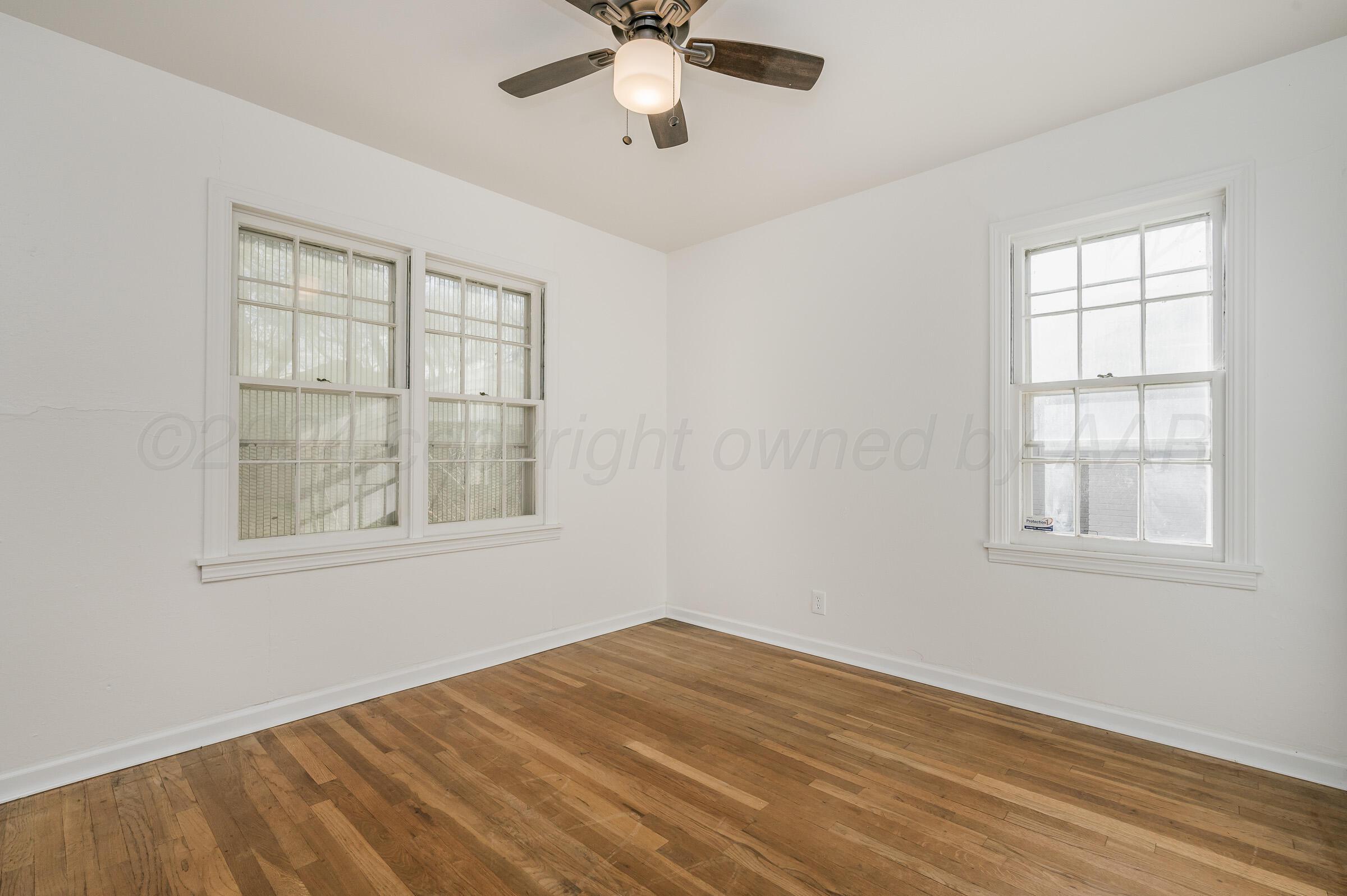 2115 South Hayden Street Amarillo, TX 79109 - Photo 17 of 27 an empty room with wooden floor chandelier fan and windows