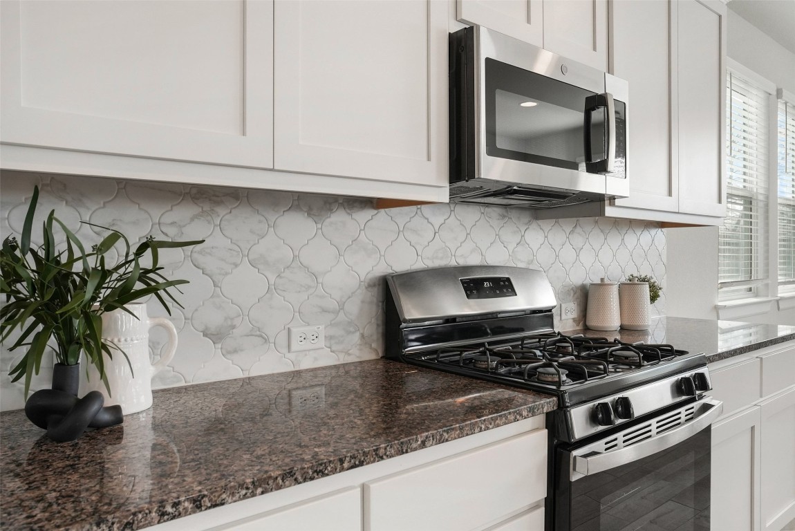113 Stone Cyn Drive Georgetown, TX 78628 - Photo 14 of 35 a kitchen with granite countertop a stove and a white cabinets