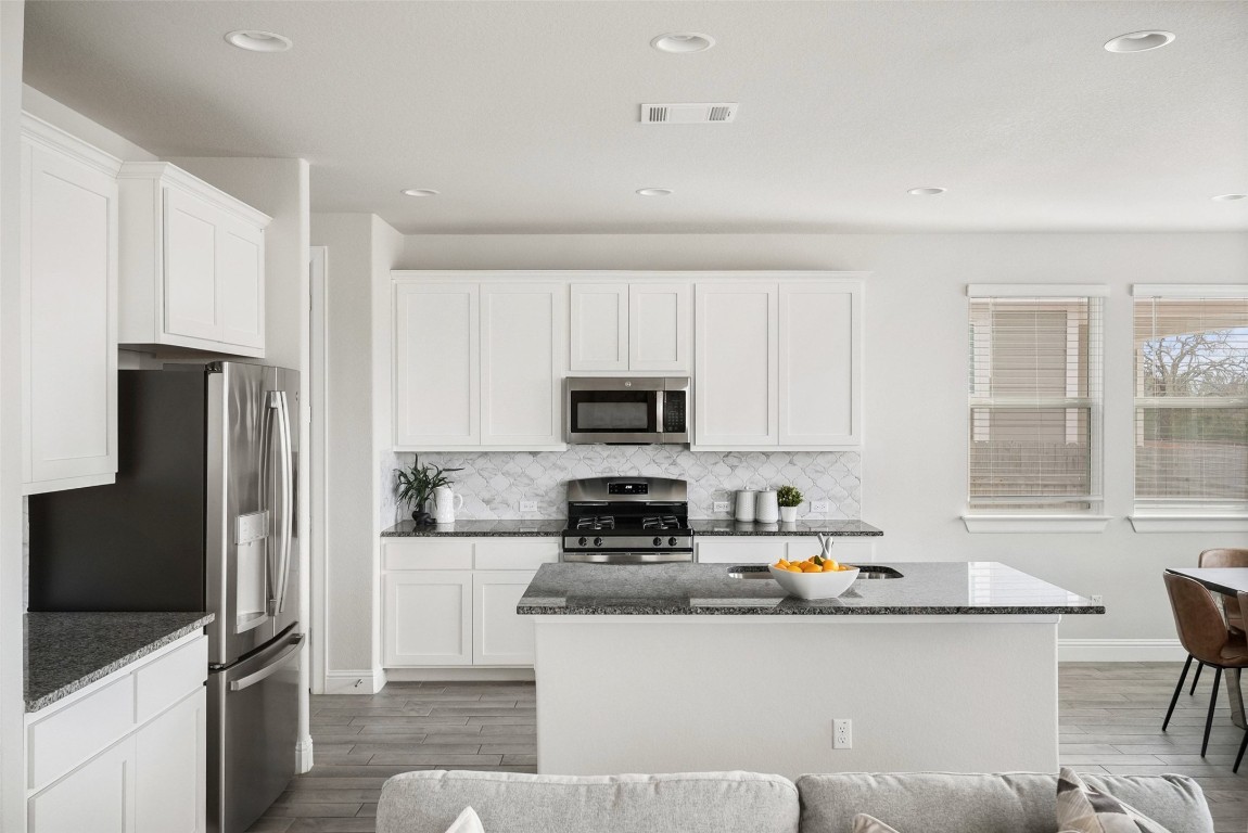 113 Stone Cyn Drive Georgetown, TX 78628 - Photo 9 of 35 a kitchen with stainless steel appliances a stove a sink a refrigerator a window and white cabinets
