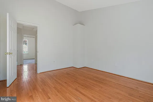a view of an empty room with wooden floor and a bathroom