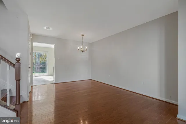 an empty room with chandelier fan and windows