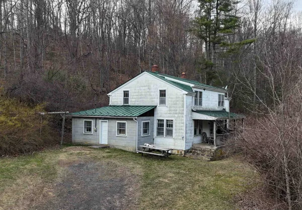 a view of a house with a yard and large tree