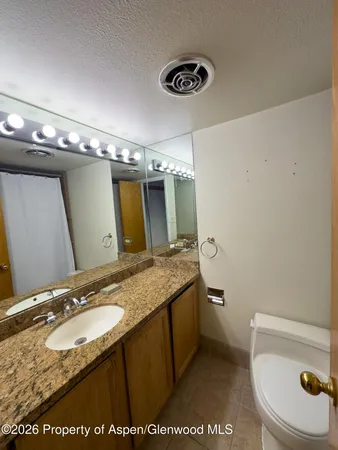 a bathroom with a granite countertop sink a mirror and a toilet