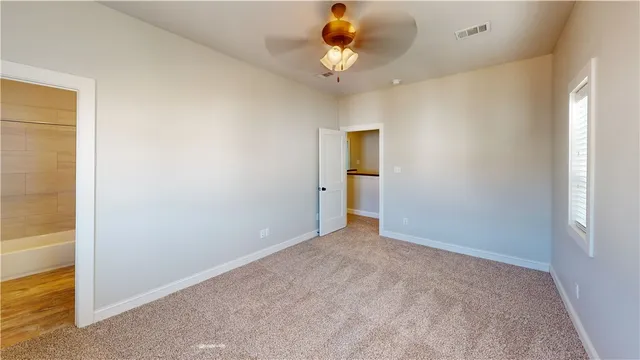 an empty room with a chandelier fan and glass door