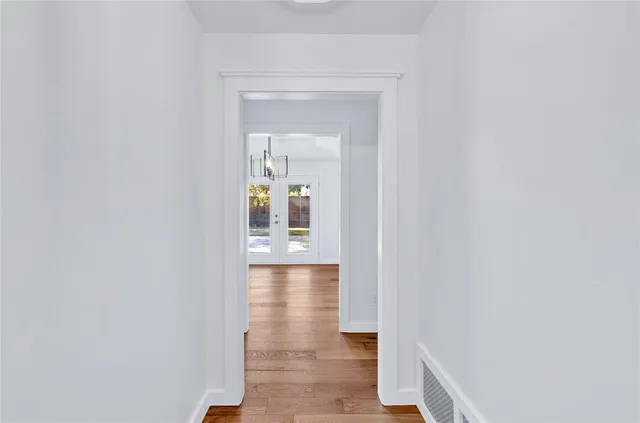 a view of a hallway with wooden floor and a bathroom