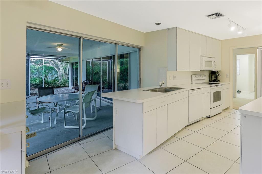 3888 Crayton Road Naples, FL 34103 - Photo 13 of 29 a kitchen with a sink and chairs