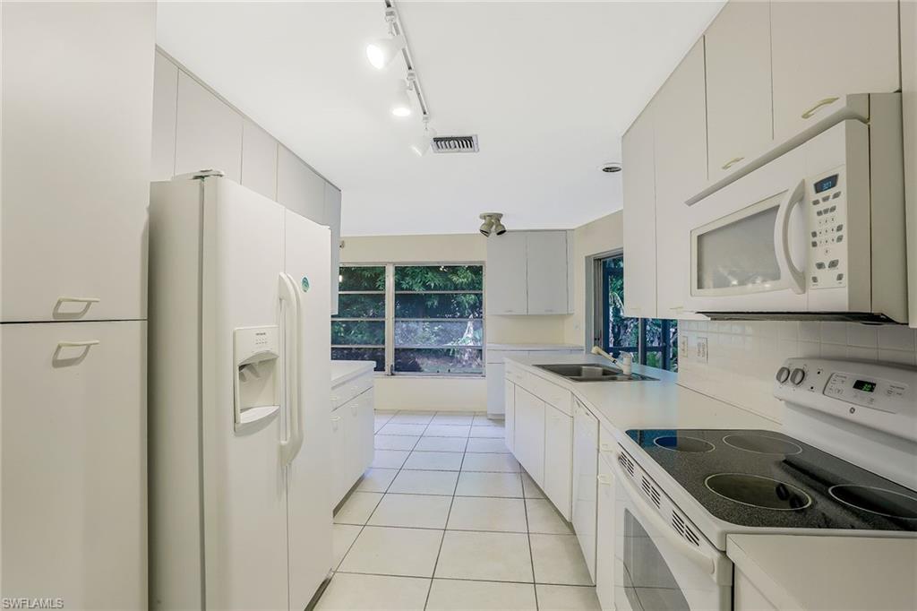 3888 Crayton Road Naples, FL 34103 - Photo 14 of 29 a kitchen with a sink a refrigerator and cabinets