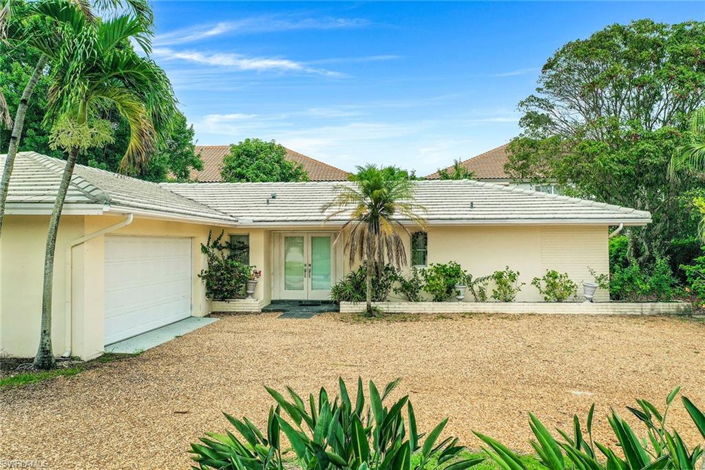3888 Crayton Road Naples, FL 34103 - Photo 23 of 29 a front view of a house with a yard and a garage