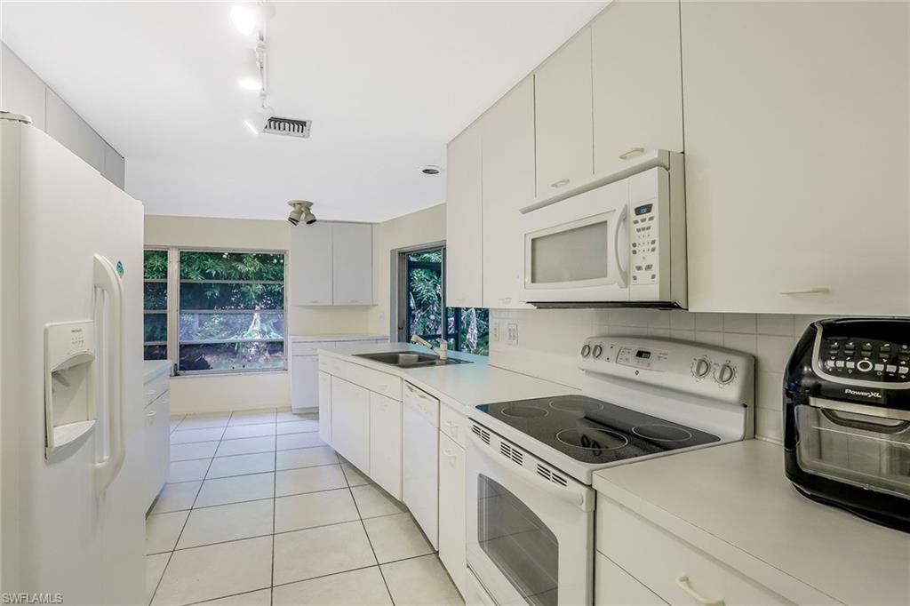 3888 Crayton Road Naples, FL 34103 - Photo 10 of 29 a kitchen with a stove a sink and a refrigerator