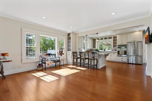 a living room with furniture a large window and wooden floor