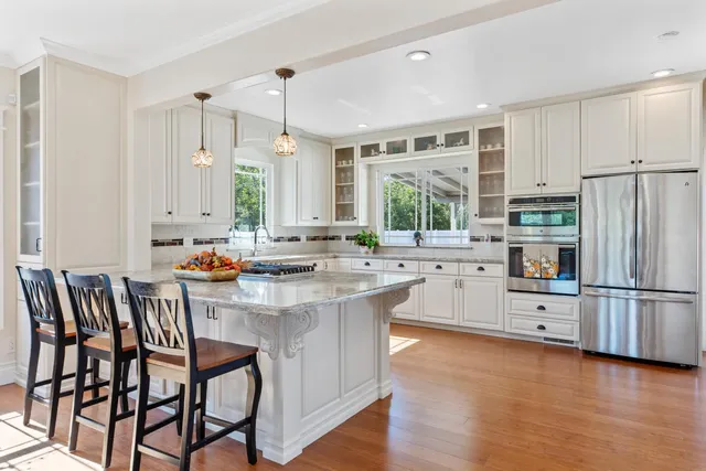 a kitchen with stainless steel appliances granite countertop a table chairs stove and refrigerator