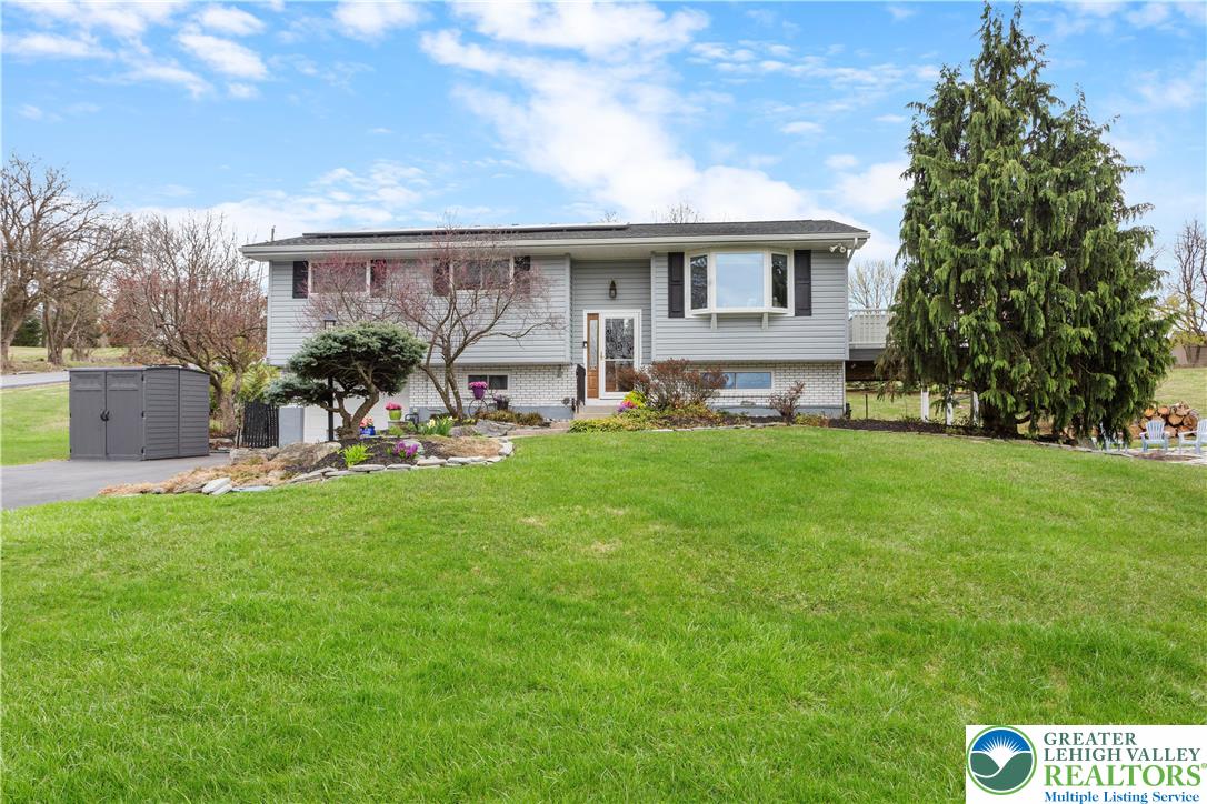 a front view of a house with a garden and trees