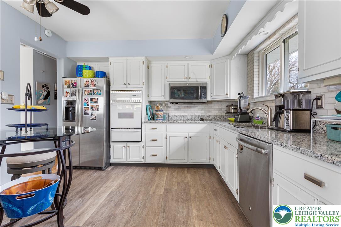 910 Gall Road Easton, PA 18040 - Photo 3 of 30 a kitchen with stainless steel appliances a stove top oven a refrigerator a sink dishwasher and white cabinets with wooden floor