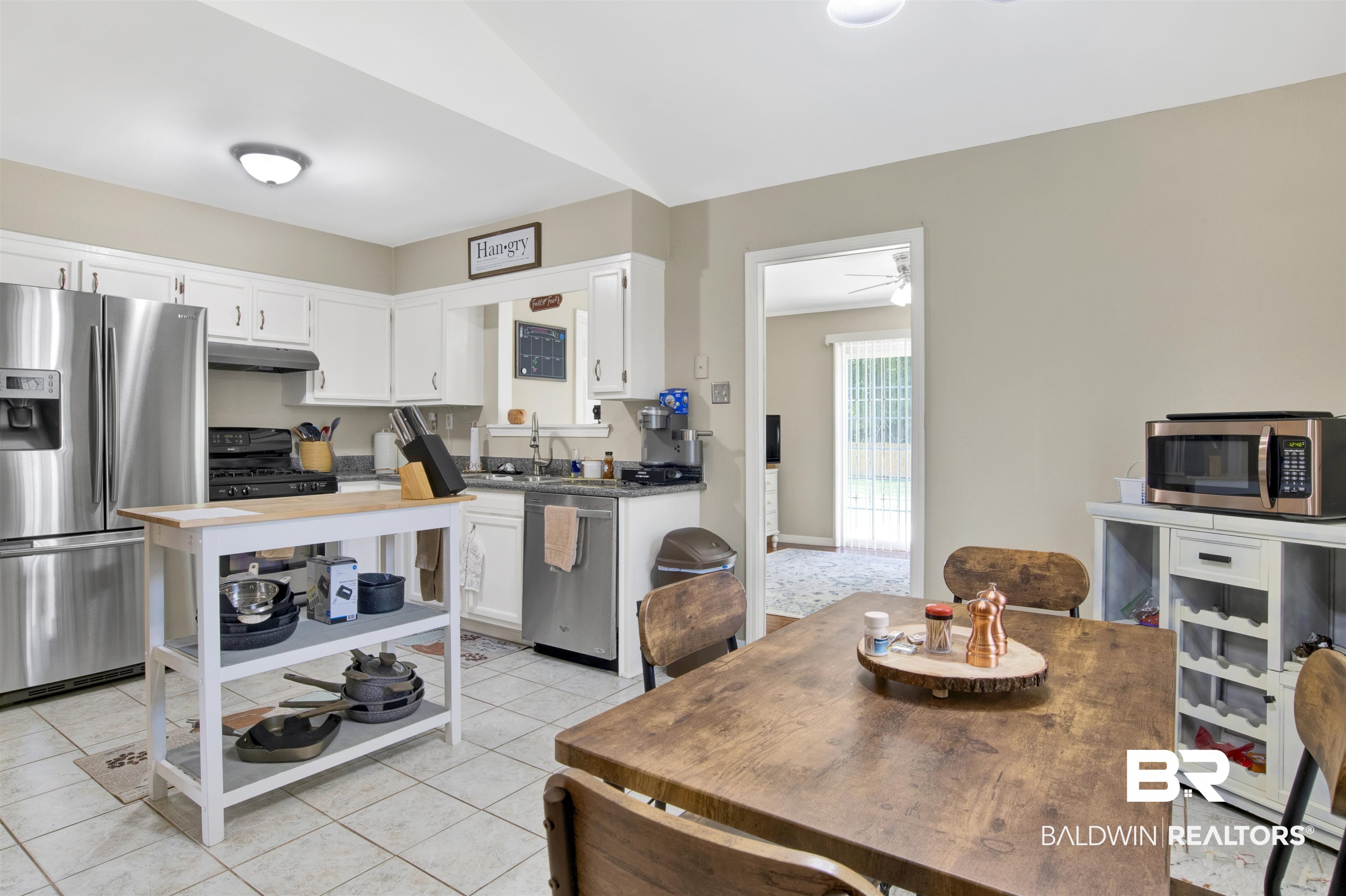 1476 Boudousquie Street Mobile, AL 36605 - Photo 14 of 34 Kitchen featuring stainless steel appliances, under cabinet range hood, white cabinetry, light tile patterned flooring, and a ceiling fan