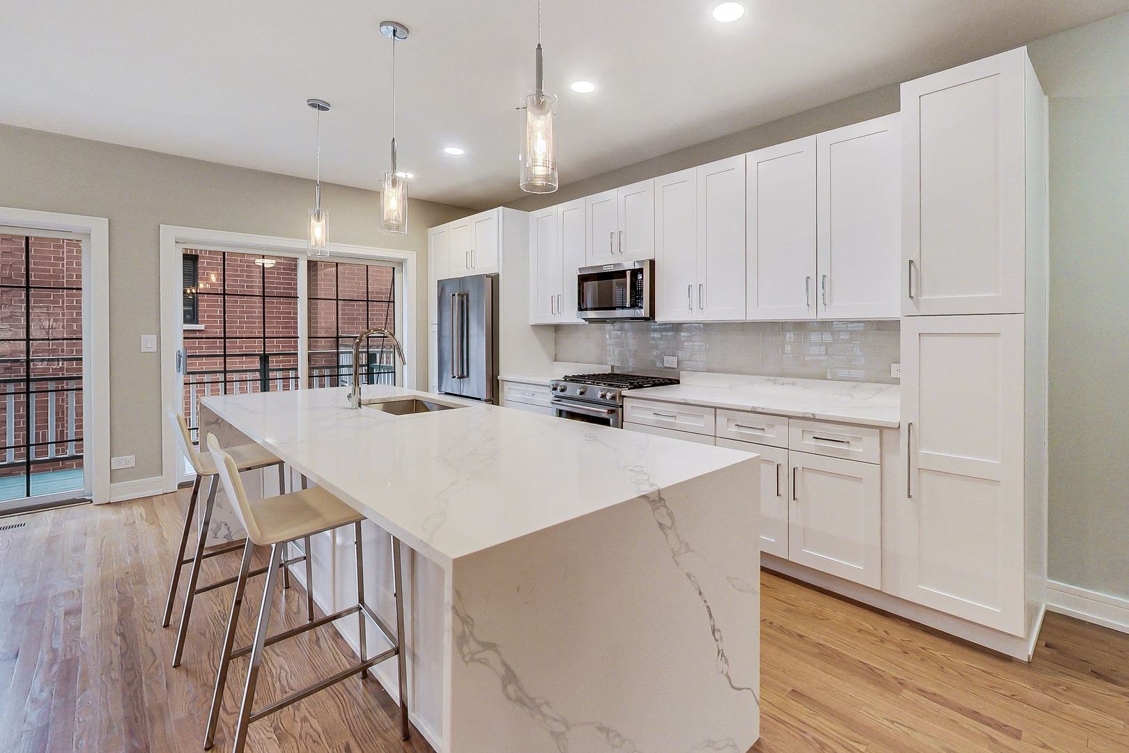 1036 West Monroe Street Chicago, IL 60607 - Photo 6 of 24 a kitchen with kitchen island a stove a sink a refrigerator and white cabinets with wooden floor