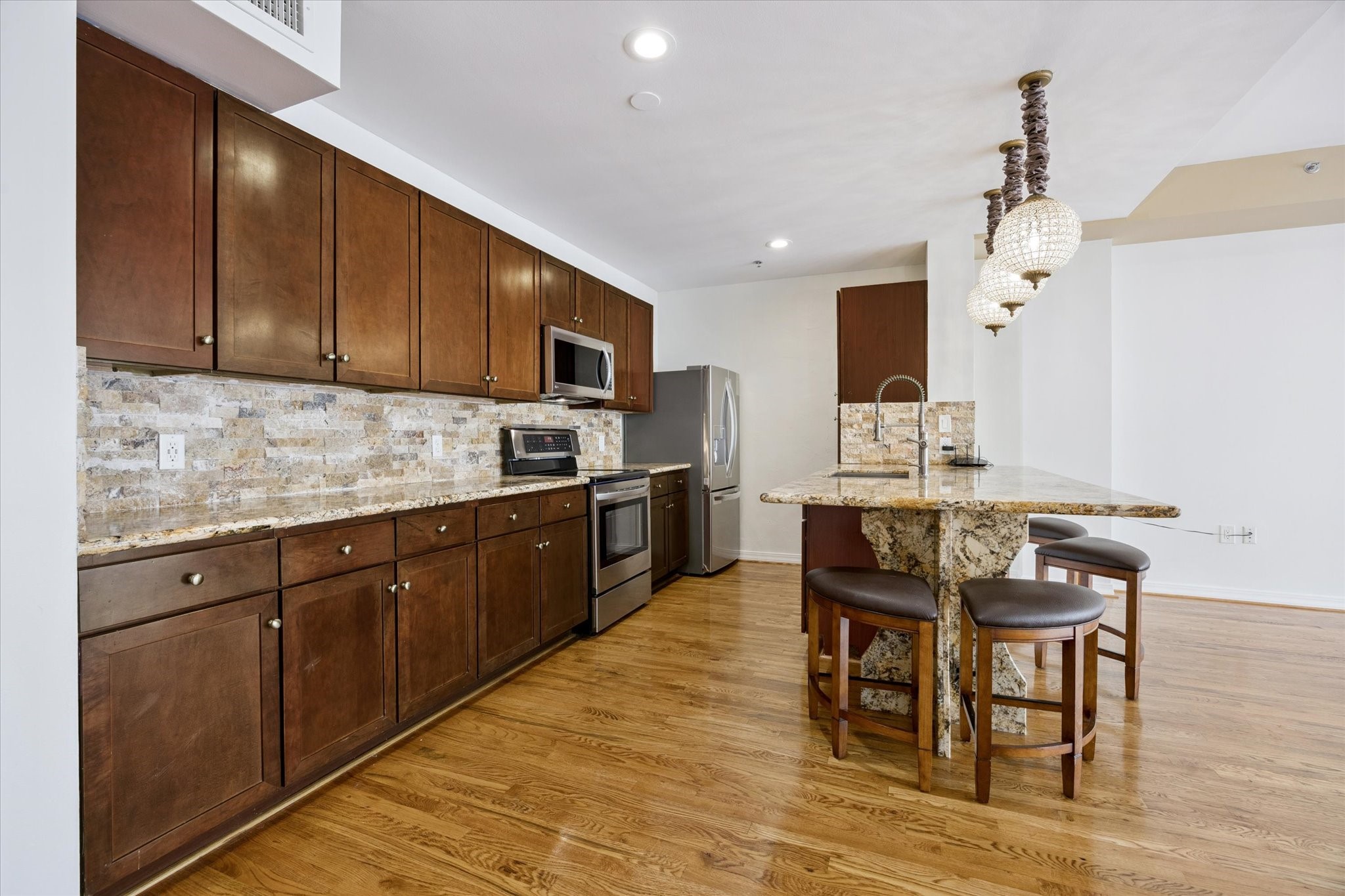 917 Main Street, Unit 1005 Houston, TX 77002 - Photo 3 of 14 a kitchen with granite countertop a table chairs microwave and cabinets