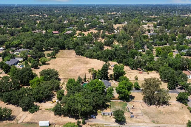 an aerial view of residential houses with outdoor space and trees