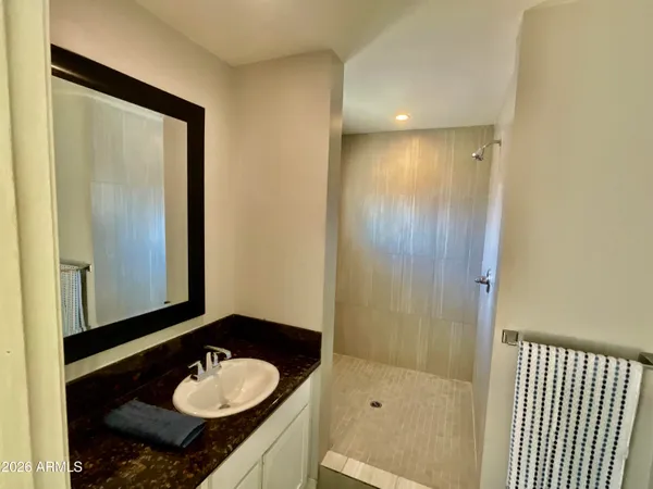 a bathroom with a sink vanity granite shower and a mirror